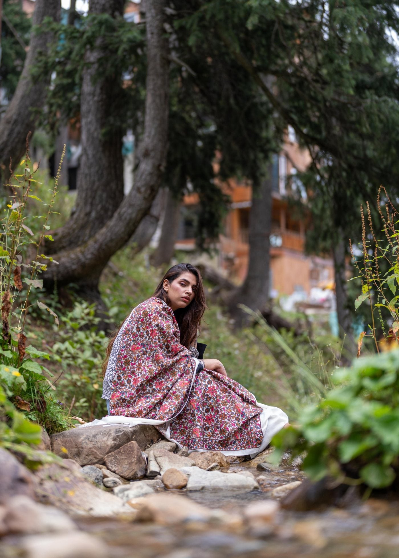 Woman in a hand-embroidered Pashmina shawl by a stream in Kashmir